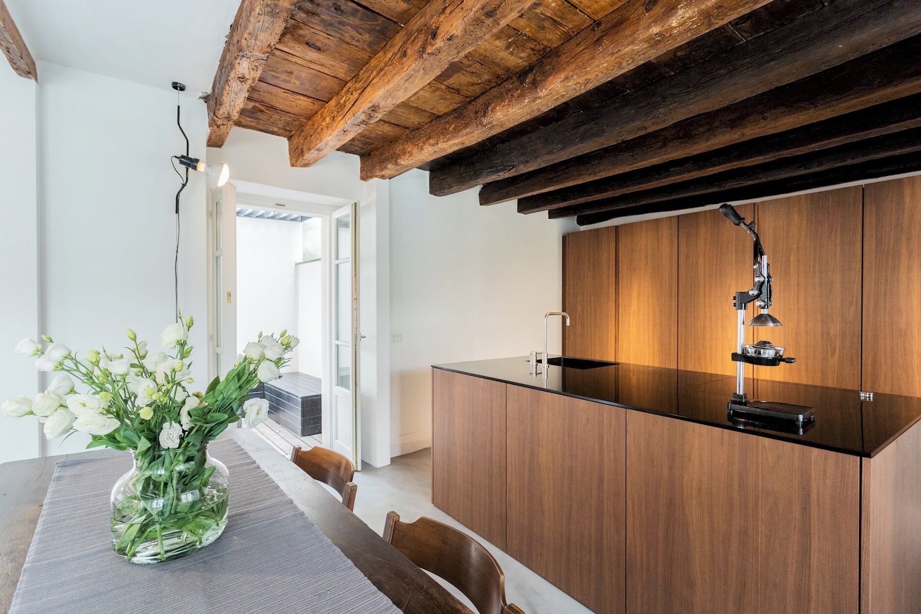 Een moderne keuken met houten kastjes, een zwart aanrecht en een hanglamp.