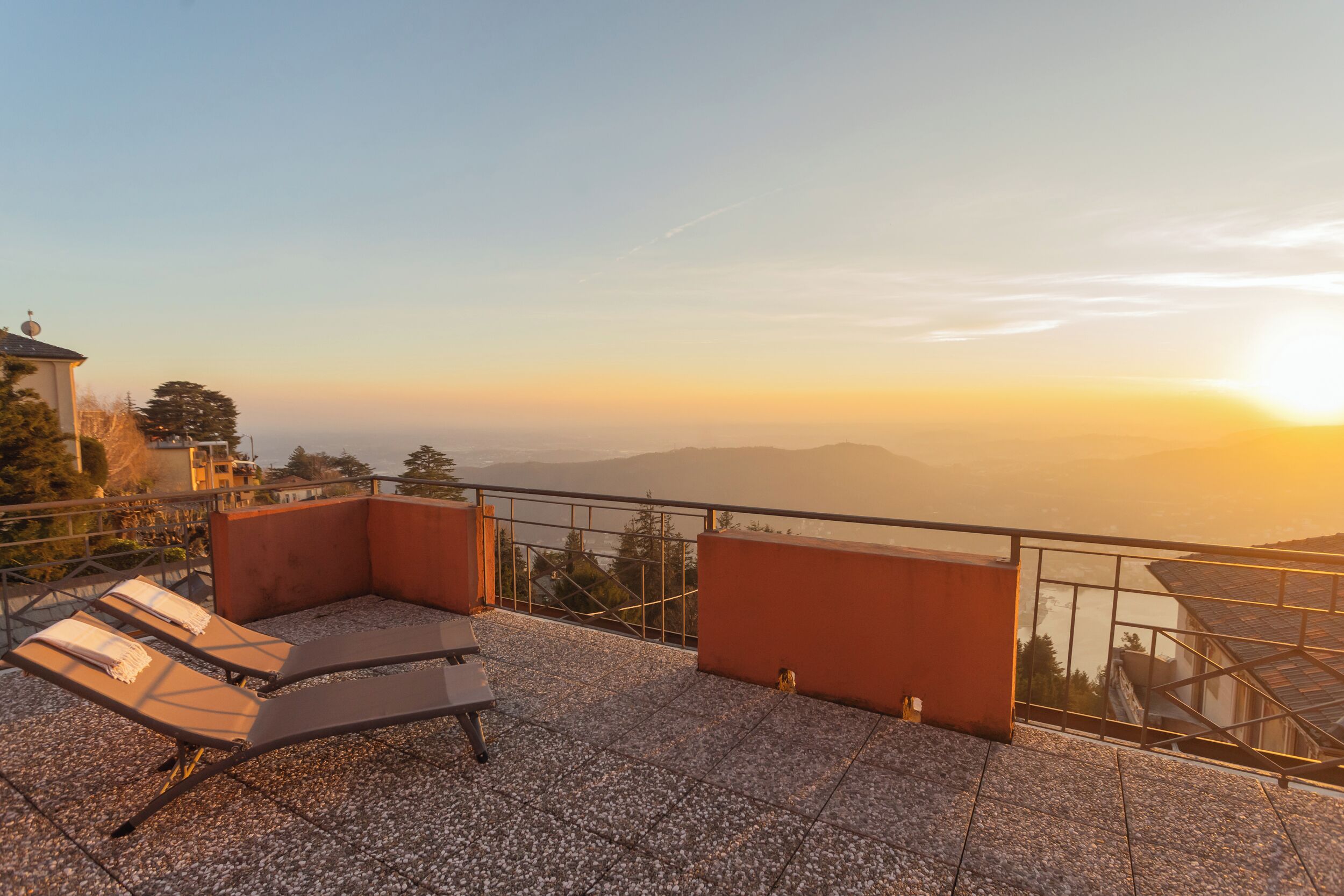 Une terrasse avec deux fauteuils et une vue sur un paysage lointain.