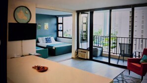 Une chambre moderne avec un grand lit, un bureau et un balcon offrant une vue sur la ville.