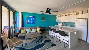 Une cuisine moderne avec des meubles blancs, un îlot central et un ventilateur de plafond.