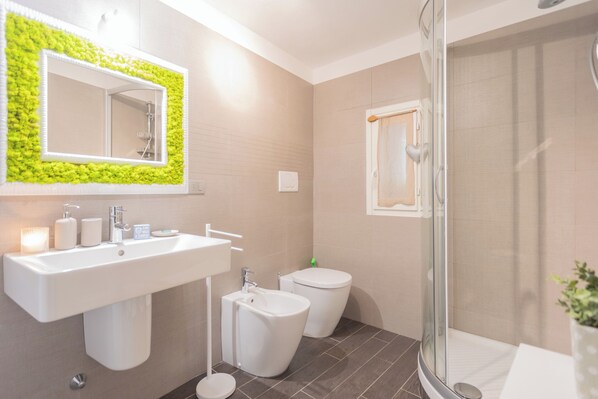 A modern bathroom with a large sink, a bidet, and a glass-enclosed shower. - The Green Nest by Lake Como by Rent all Como (Blevio)
