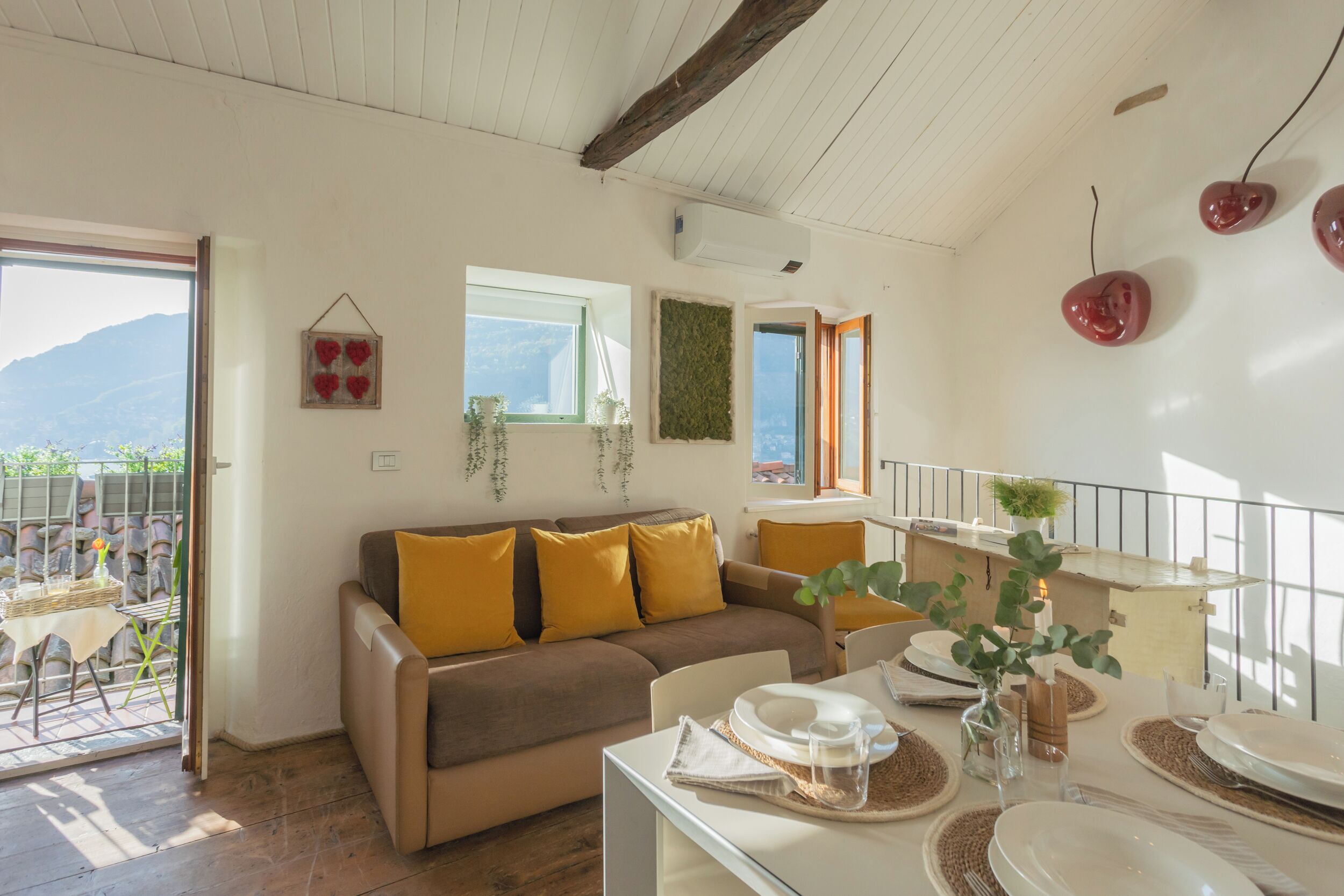 Un salón acogedor con un sofá, una mesa de comedor para dos personas y vistas al exterior.