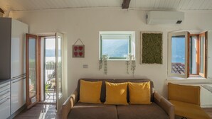 Una sala de estar con sofá, ventana con vistas y equipo de aire acondicionado.