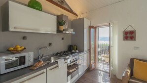 Una cocina moderna con microondas, estufa y horno integrados, un lavamanos y una ventana con vistas a un balcón.
