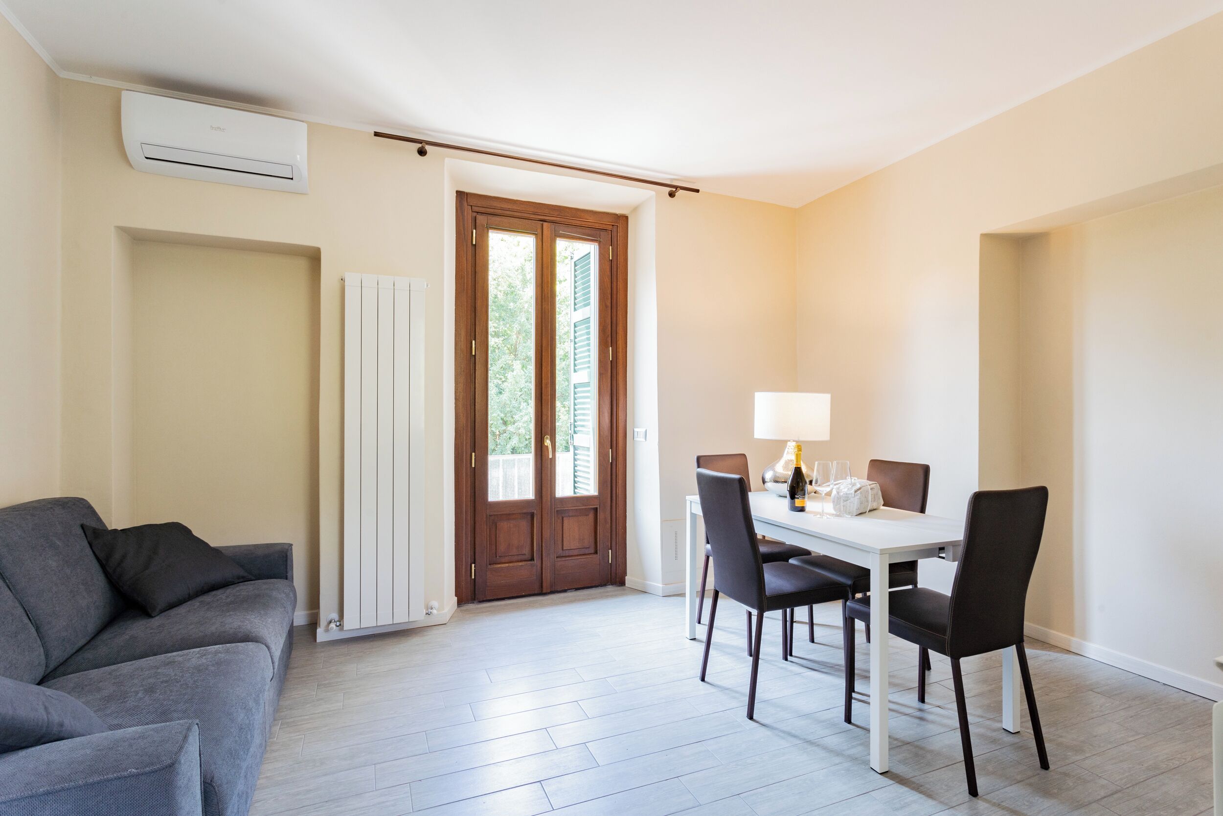 Un salon moderne avec un canapé gris, une table à manger avec des chaises et un radiateur blanc.