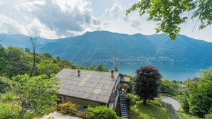 A house with a metal roof, a staircase leading to a deck, and a view of mountains and a lake. - Top Lake View Villetta by Rent all Como (Cernobbio)
