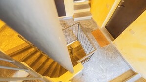 Un escalier avec une rampe en métal, une plateforme recouverte de moquette et une porte en bas.