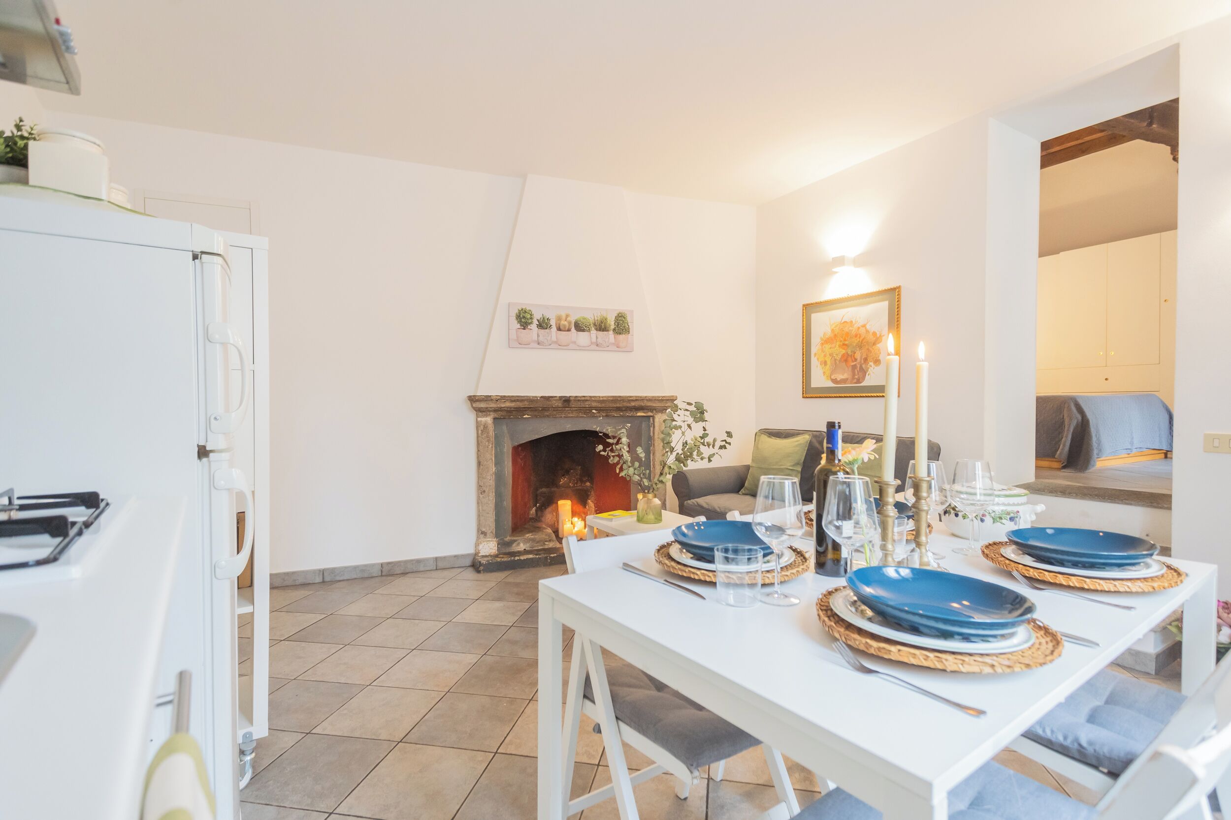 A dining area with a white table set for four, a fireplace, and a cozy seating area.