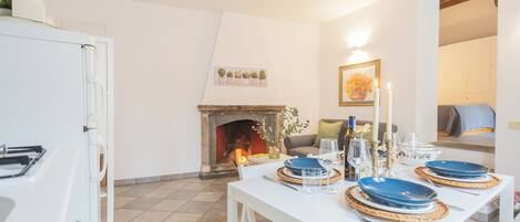 A dining area with a white table set for four, a fireplace, and a cozy seating area.