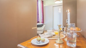 A breakfast table with a plate of kiwi slices, a glass of orange juice, a candle, and a bottle of water.