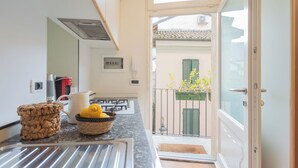 A kitchen with a granite countertop, a coffee maker, a kettle, and a basket with lemons.