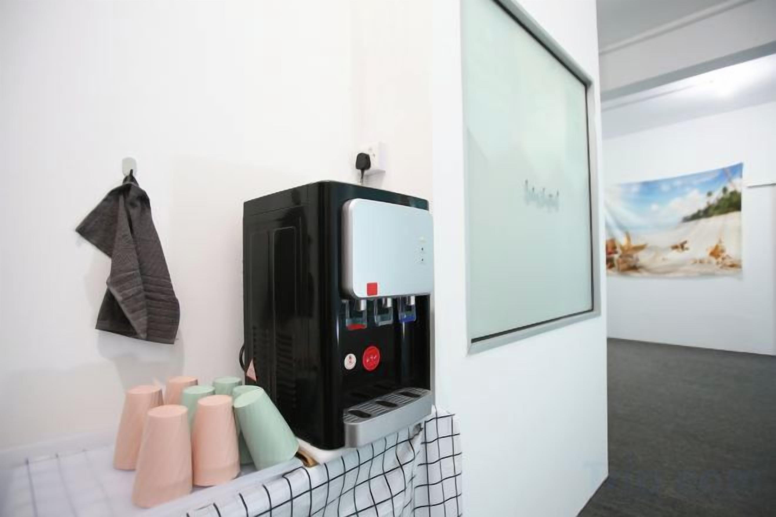 A water dispenser with a glass door, a towel rack, and a framed picture on the wall.