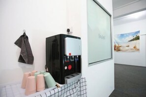 Een waterdispenser met een glazen deur, een handdoekrek en een lijst met een afbeelding aan de muur.