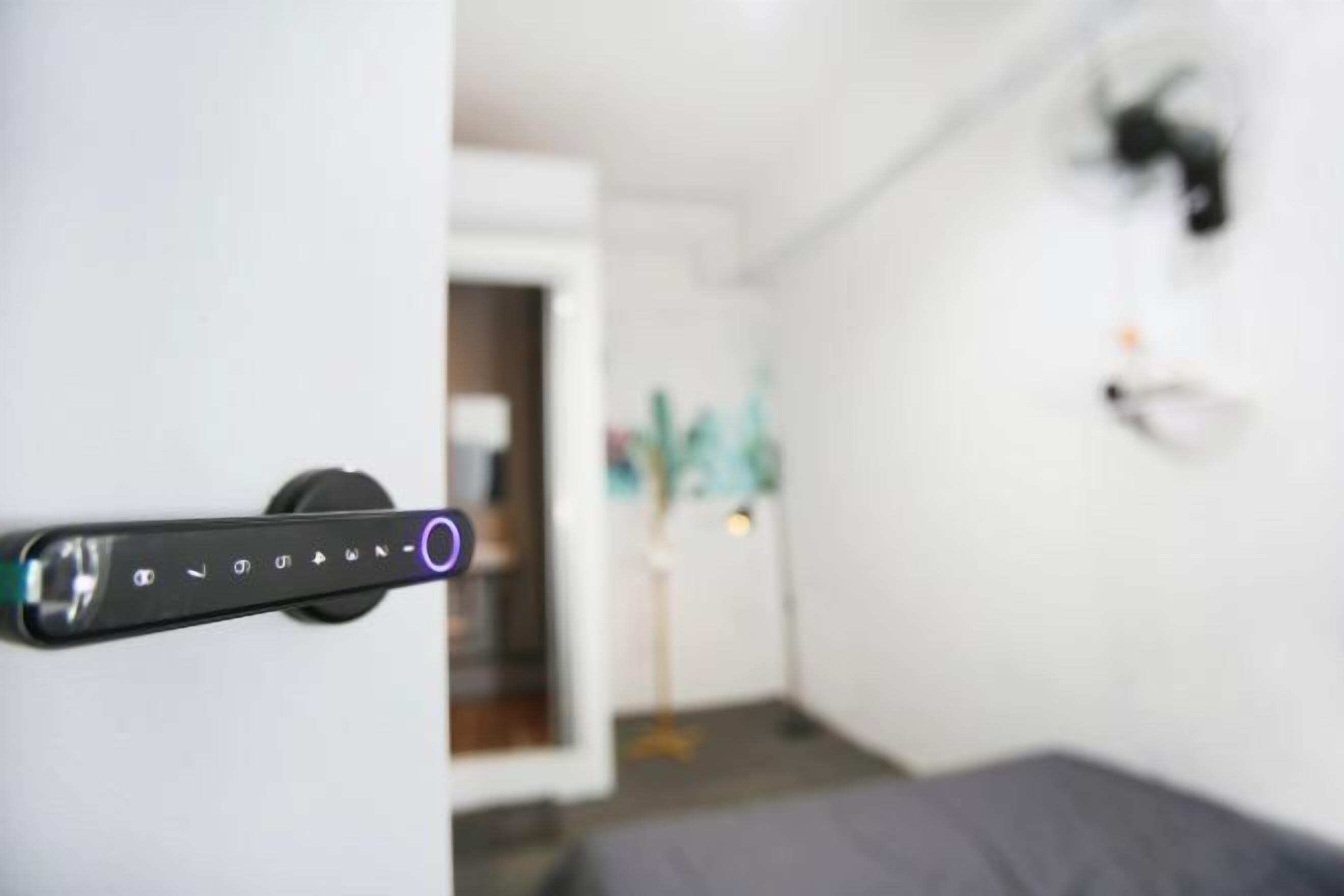 A door handle with a control panel, a bed, and a wall-mounted light fixture.