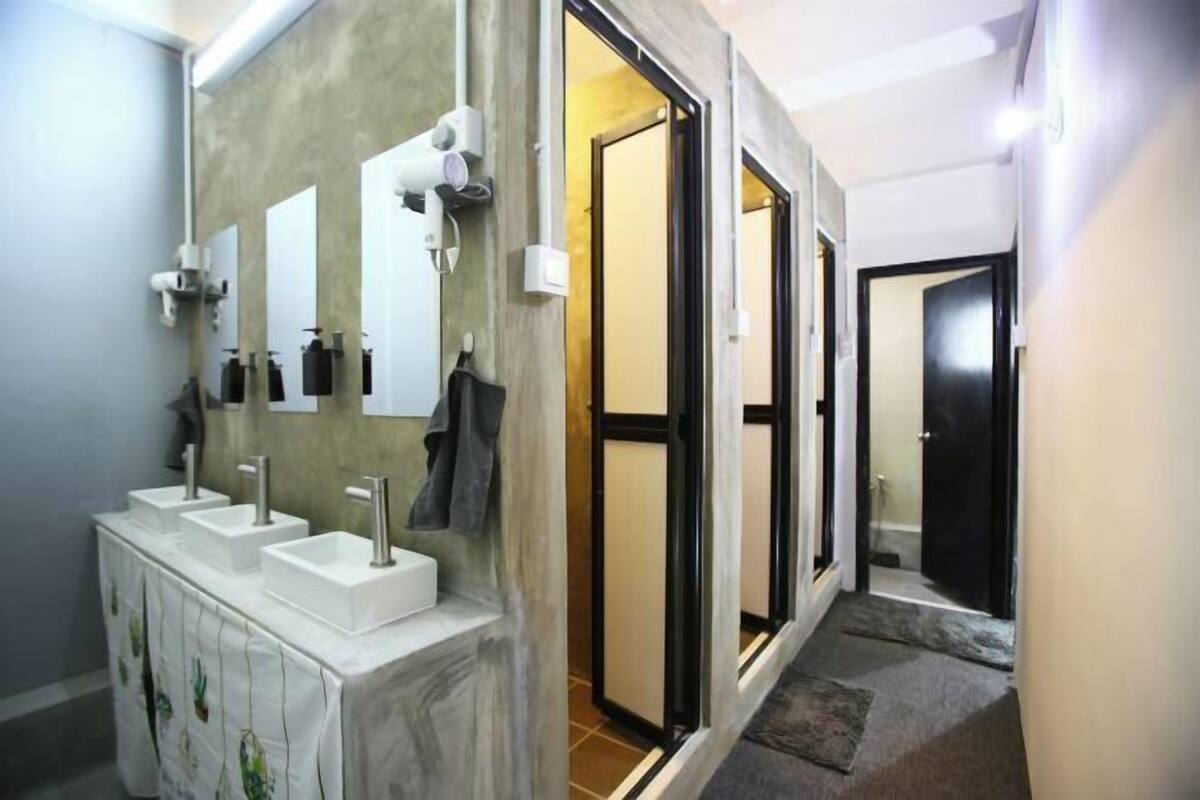 Casa de banho com três lavatórios, um espelho e um porta-toalhas.