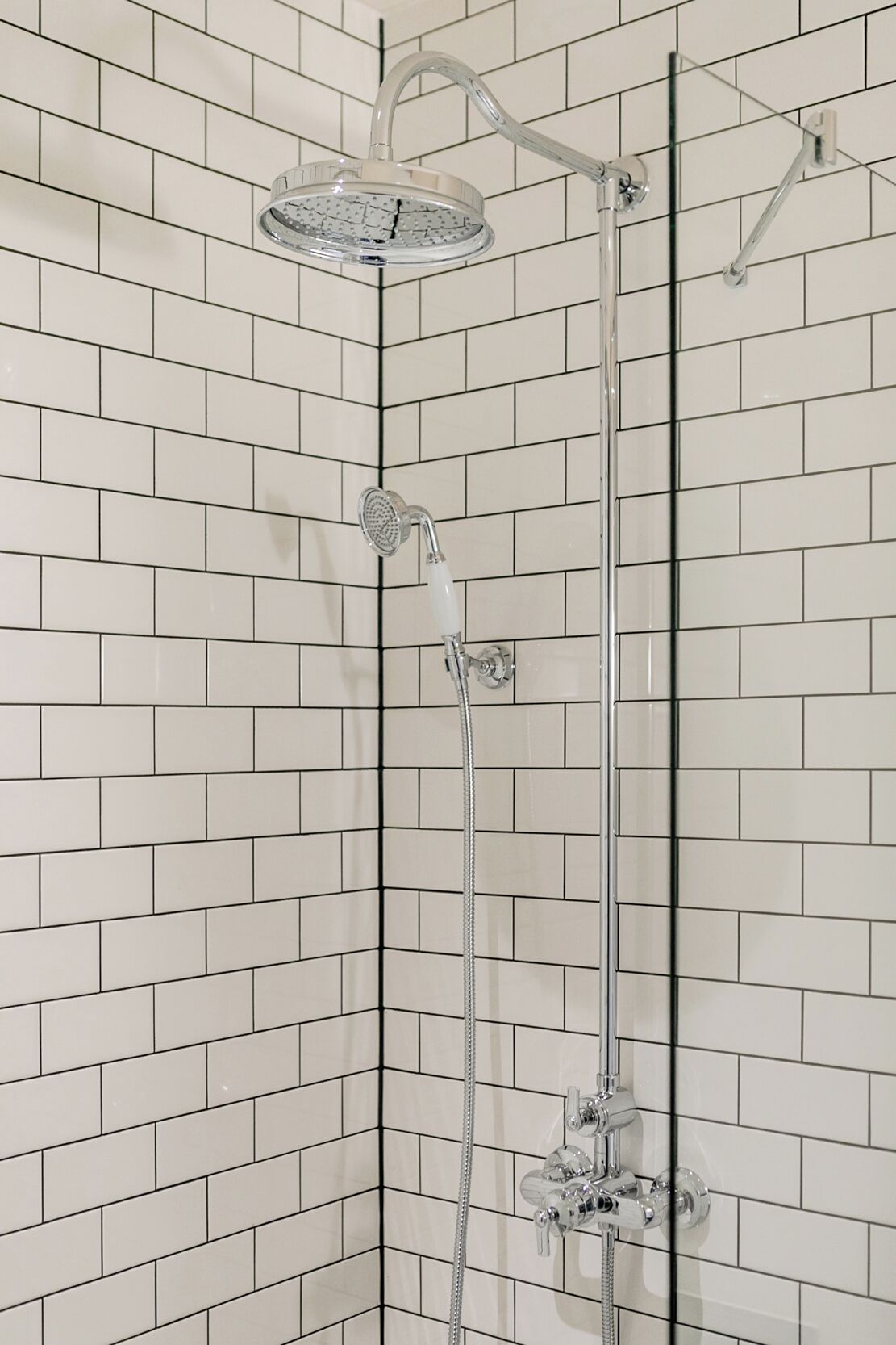 Eine Dusche mit Handbrause und Armatur an der Wand.