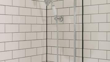 Eine Dusche mit Handbrause und Armatur an der Wand.