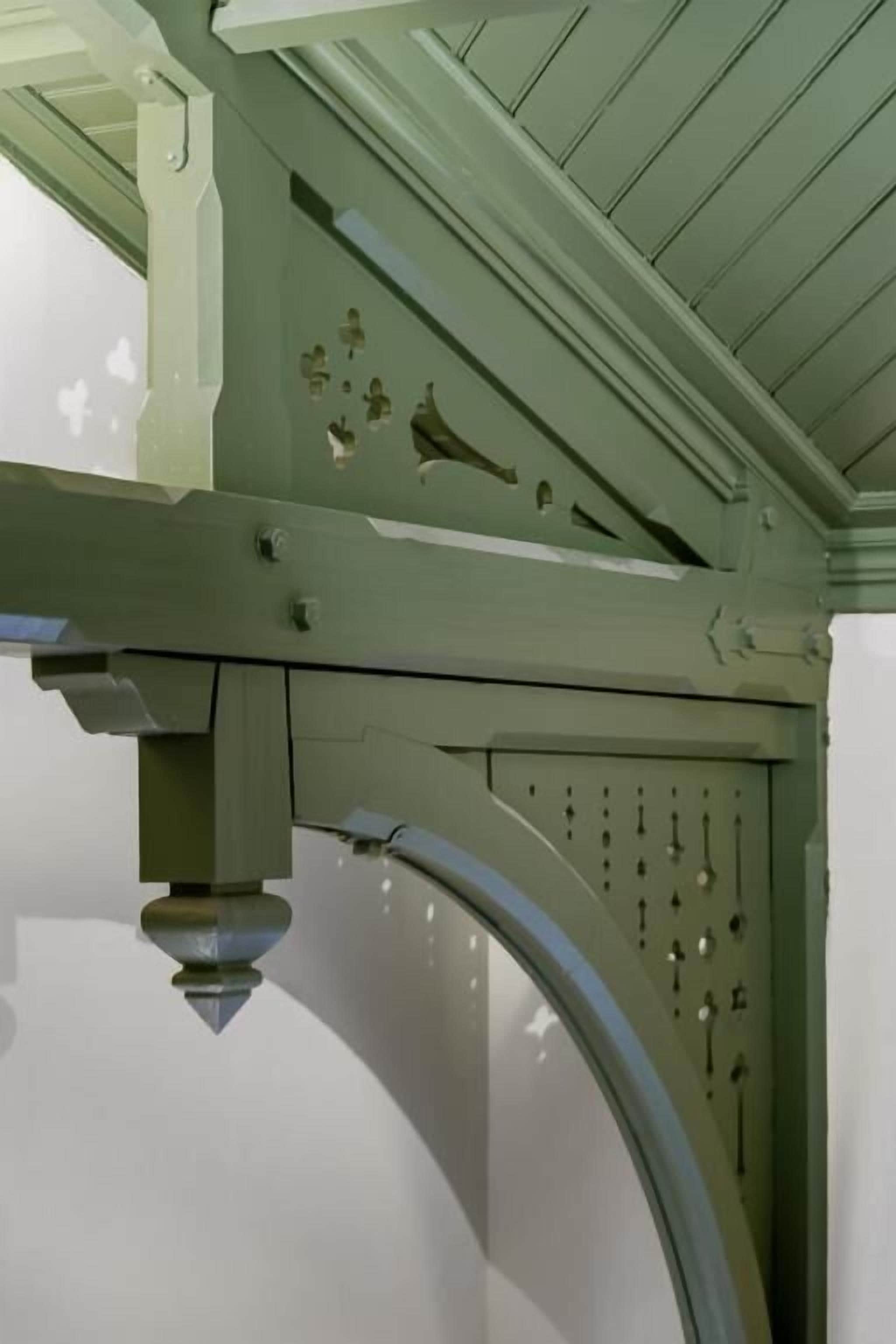 A green metal structure with a curved pipe and several holes, likely part of a mechanical system.