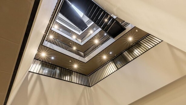 Et mere etagers interiør med et moderne design, der inkluderer et centralt atrium med et glasloft og flere balkoner.