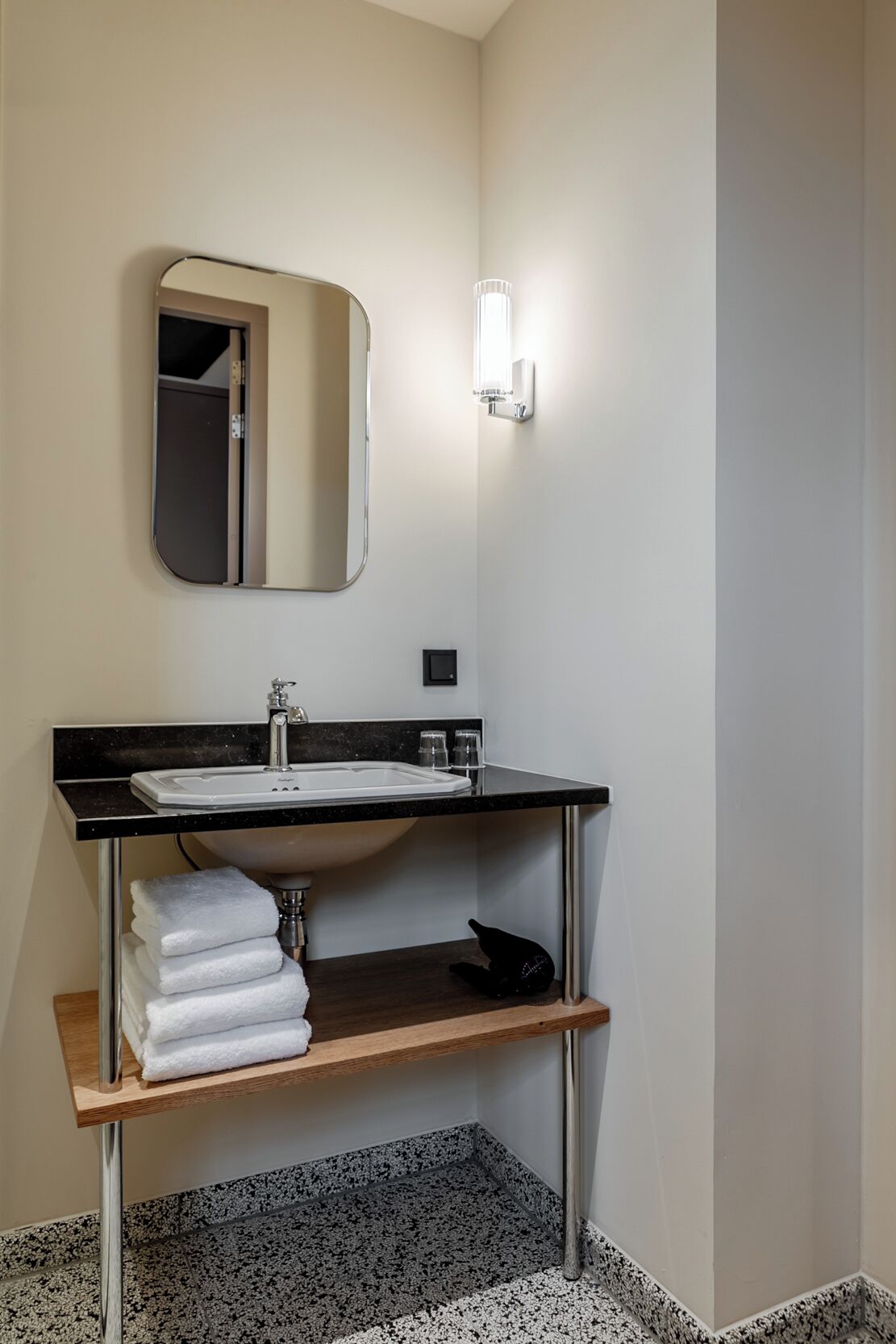 Un baño moderno con lavamanos de encimera negro, un espejo y un perchero para toallas.