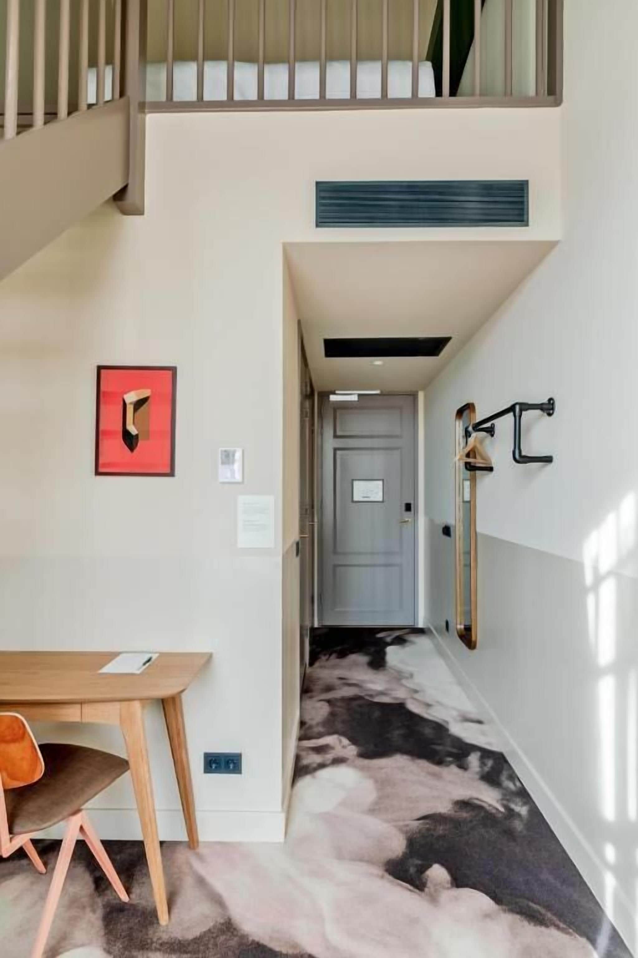 Un interior moderno con una escalera, un comedor y un pasillo que lleva a una puerta.