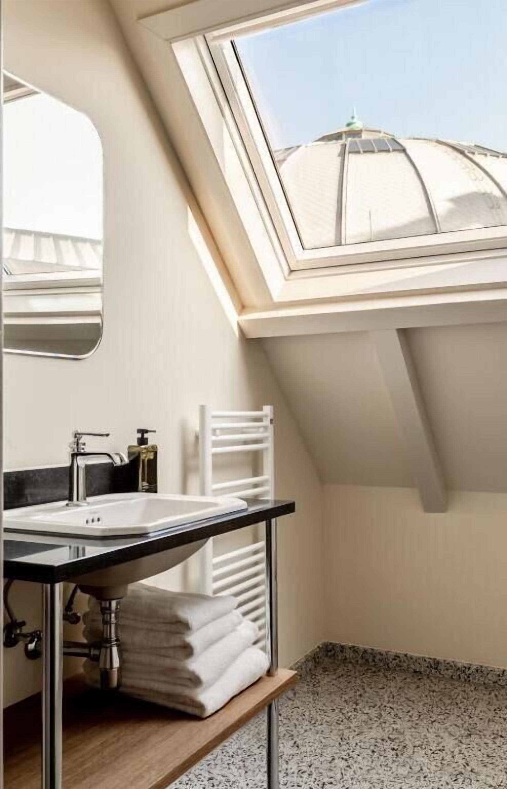 A modern bathroom with a skylight, a sink, and a towel rack.