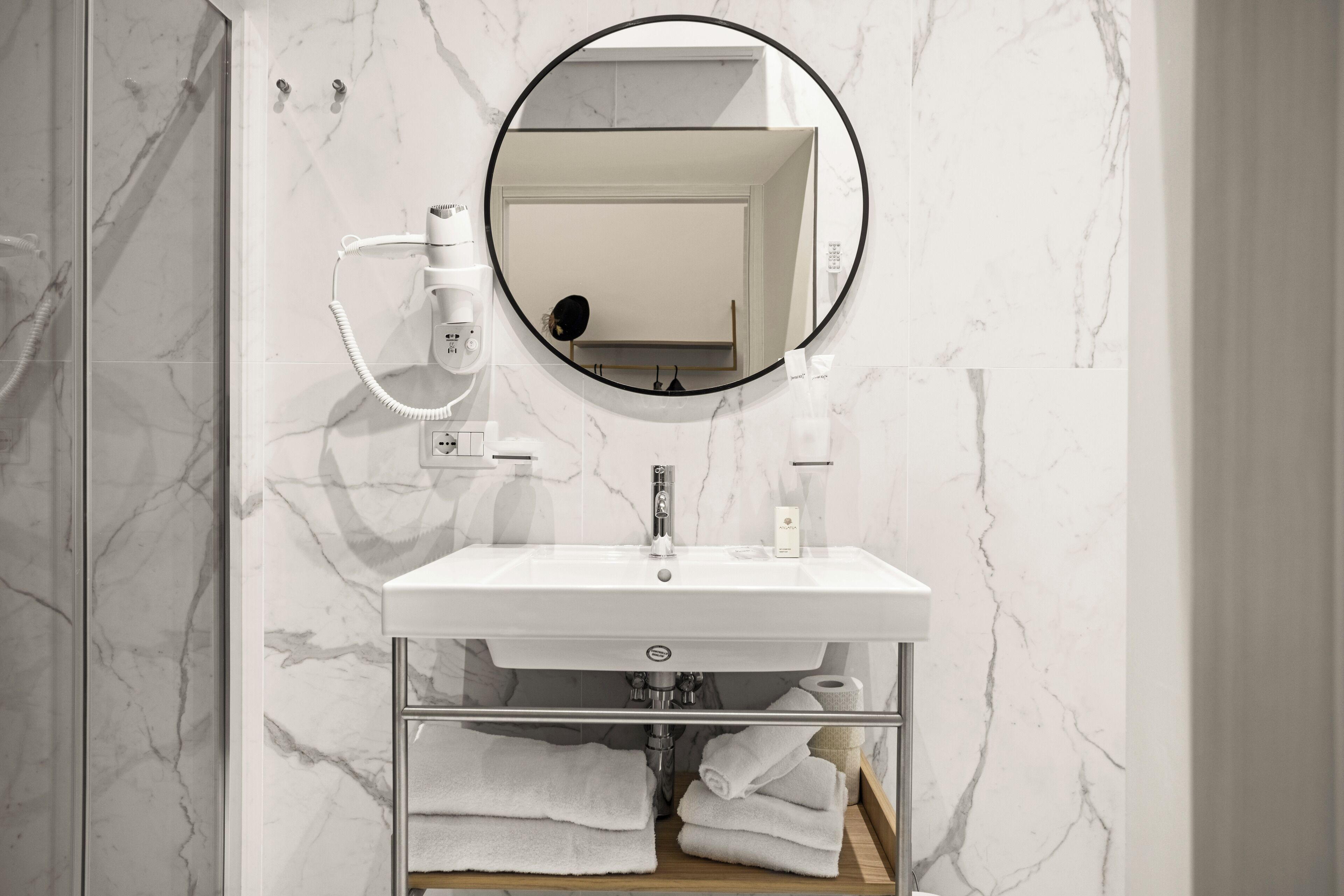 Un baño con lavamanos blanco, espejo y barra para toallas.