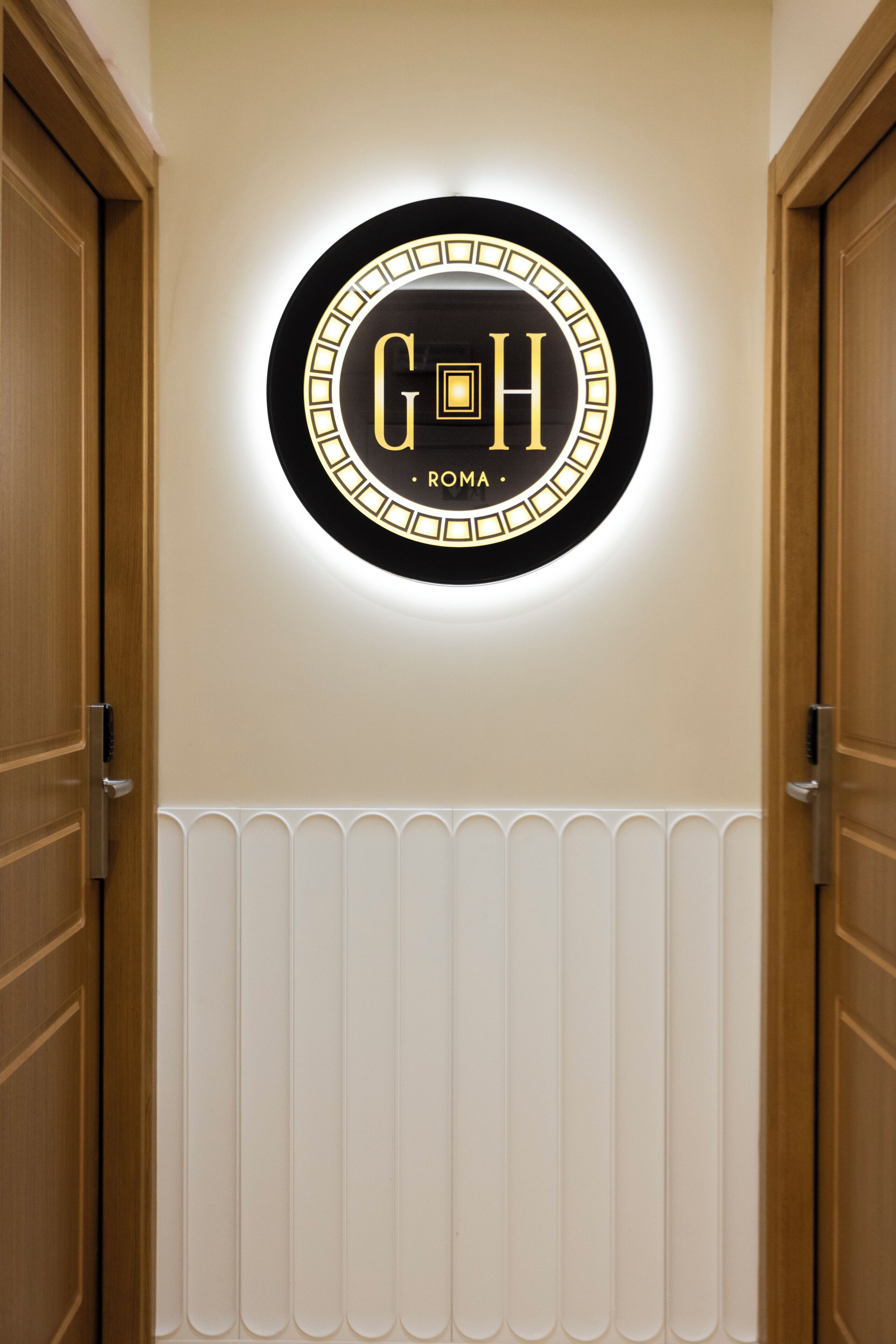 A circular sign with the letters "G H" and the word "ROMA" on a wall.