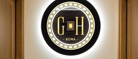 A circular sign with the letters "G H" and the word "ROMA" on a wall.