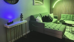 Uma sala de estar moderna com um sofá verde, uma mesinha e um objeto decorativo na parede.