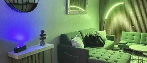 Un salon moderne avec un canapé vert, une petite table et un élément décoratif mural.
