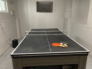 Una mesa de ping pong con un altavoz y dos palas.