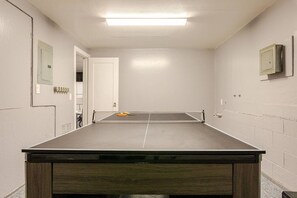 Une pièce avec une table de ping-pong, une porte et un tableau électrique fixé au mur.