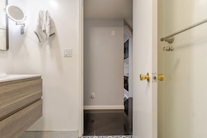 Un baño con espejo, toallero y puerta que da a un armario.