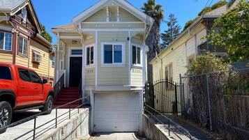 A two-story house with a garage, a red SUV parked in front, and a clear blue sky.
