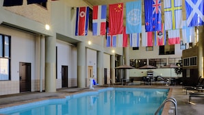 Una piscina con banderas, sillas de descanso y sombrillas.