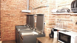 A kitchen area with brick walls, a microwave, a coffee machine, and a dish rack.