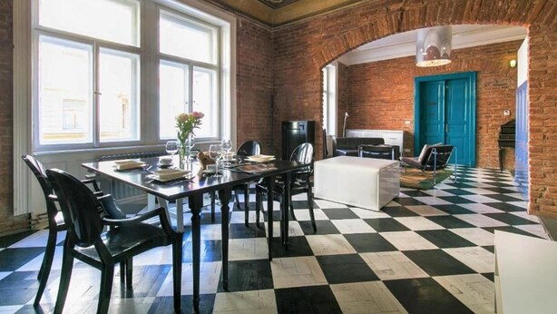 A dining area with a checkered floor, brick walls, and large windows.