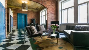 A living room with a checkered floor, a brick wall, and a large window.
