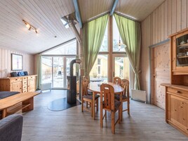 Un intérieur de chalet chaleureux avec un coin repas, des meubles en bois et un poêle à bois.