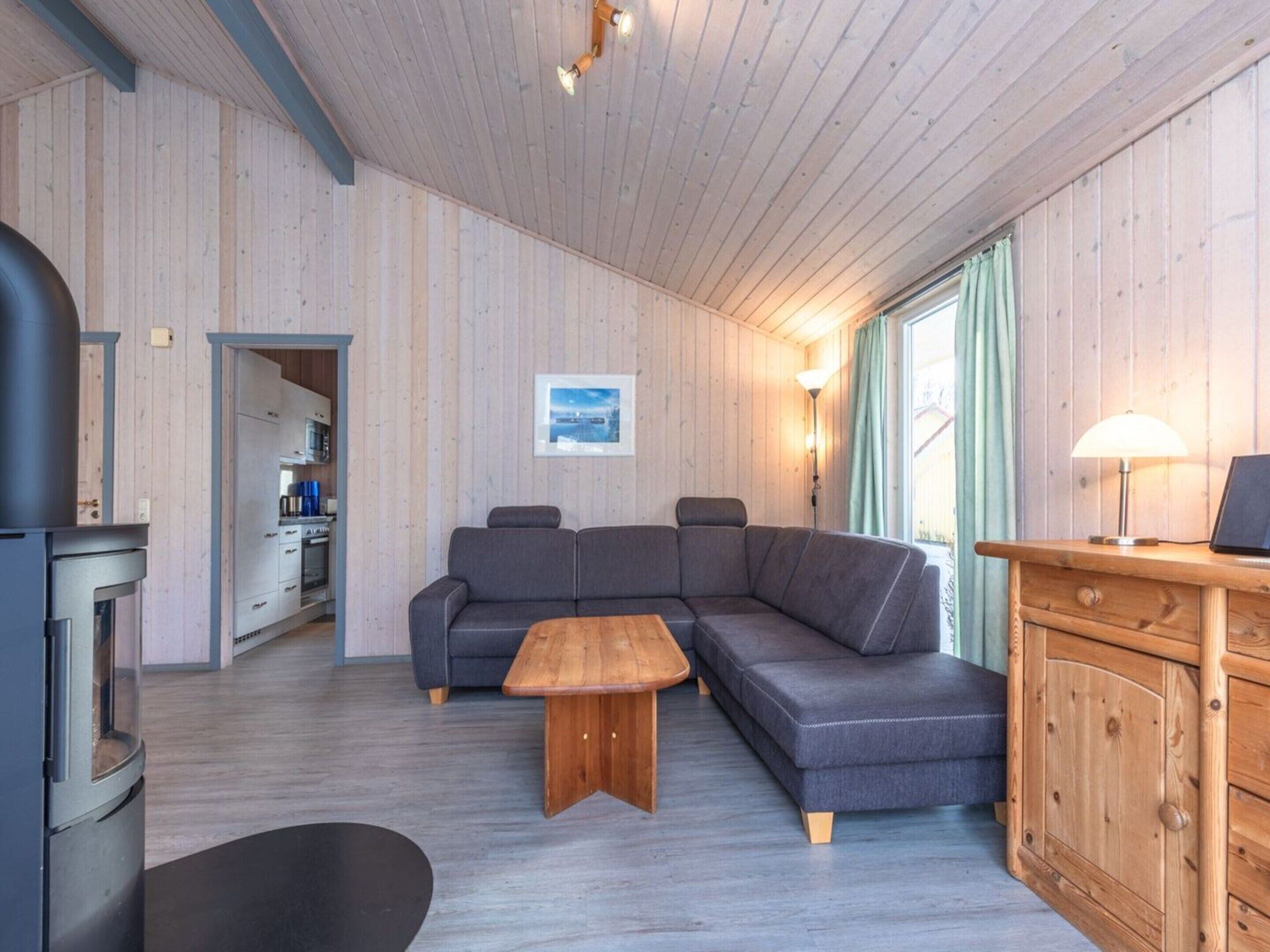 Un soggiorno moderno con un divano componibile, un tavolino in legno e una cucina visibile attraverso una porta aperta.