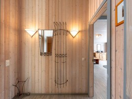 Un couloir aux murs lambrissés, orné de deux miroirs et de deux lampes fixées au mur.