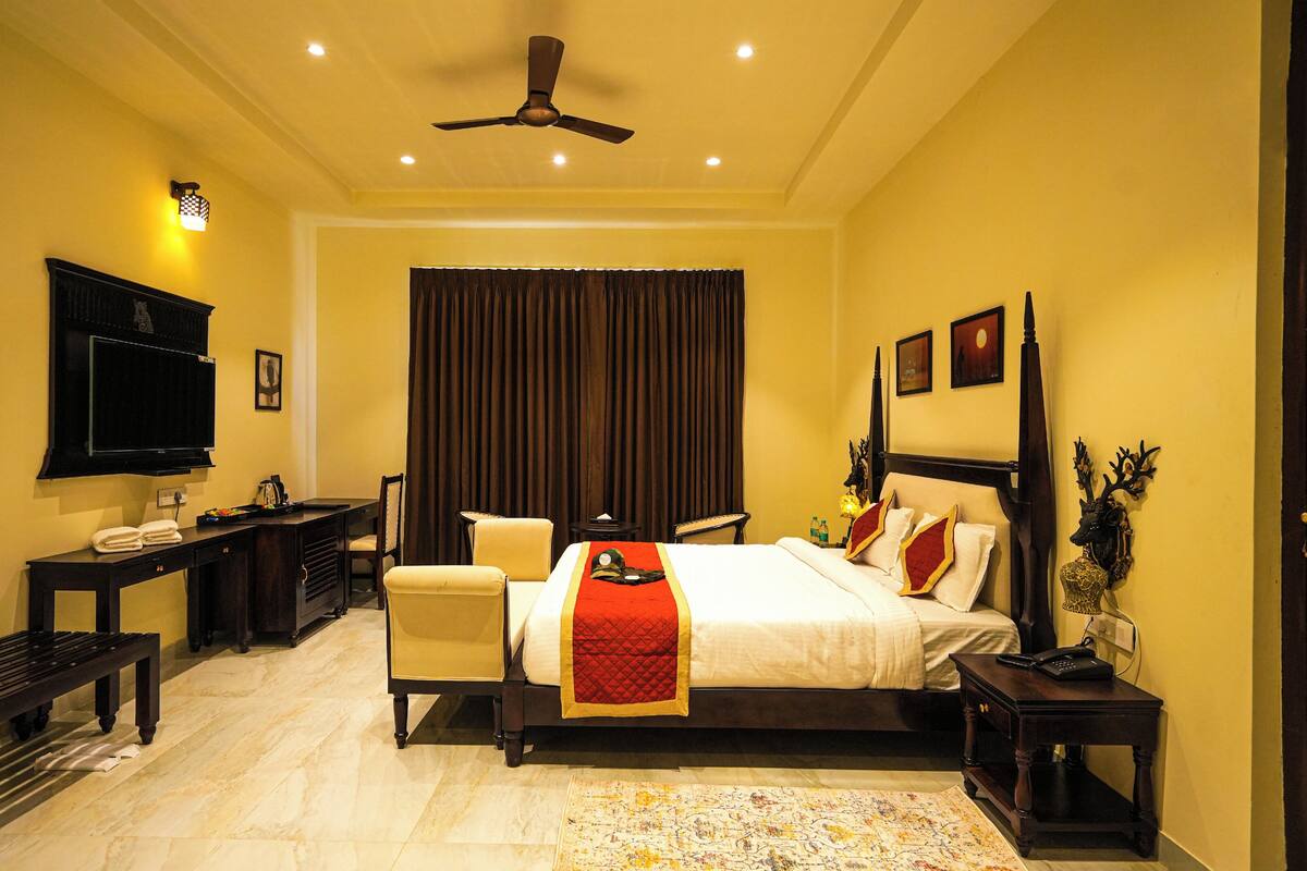 Ein Hotelzimmer mit Bett, Schreibtisch, Stuhl, Fernseher und Deckenventilator.