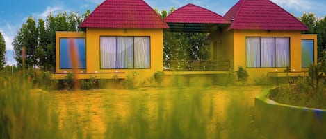 Ein gelbes Gebäude mit roten Dächern, großen Fenstern und einem Weg davor.