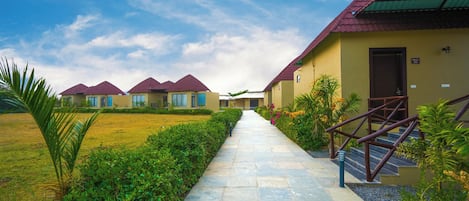 A pathway leading to a row of yellow buildings with red roofs, each with a door and windows, and a sign indicating room number 106.