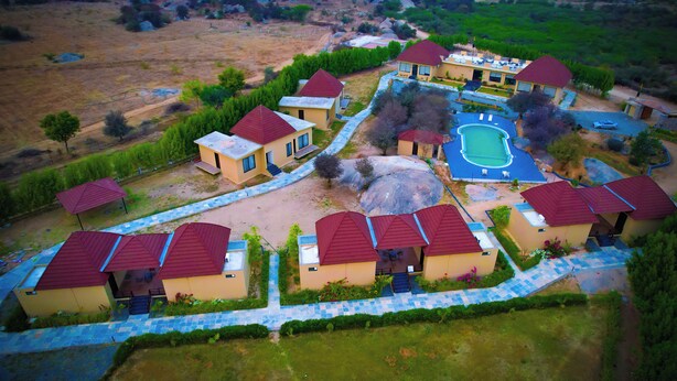 An aerial view of a residential area with multiple houses, a swimming pool, and a well-maintained lawn. - Jawai Zinc Journey by The Fern (Bali)