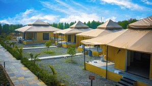 A row of yellow tents with awnings, arranged in a row with a gravel path and small trees in between. - Jawai Zinc Journey by The Fern (Bali)