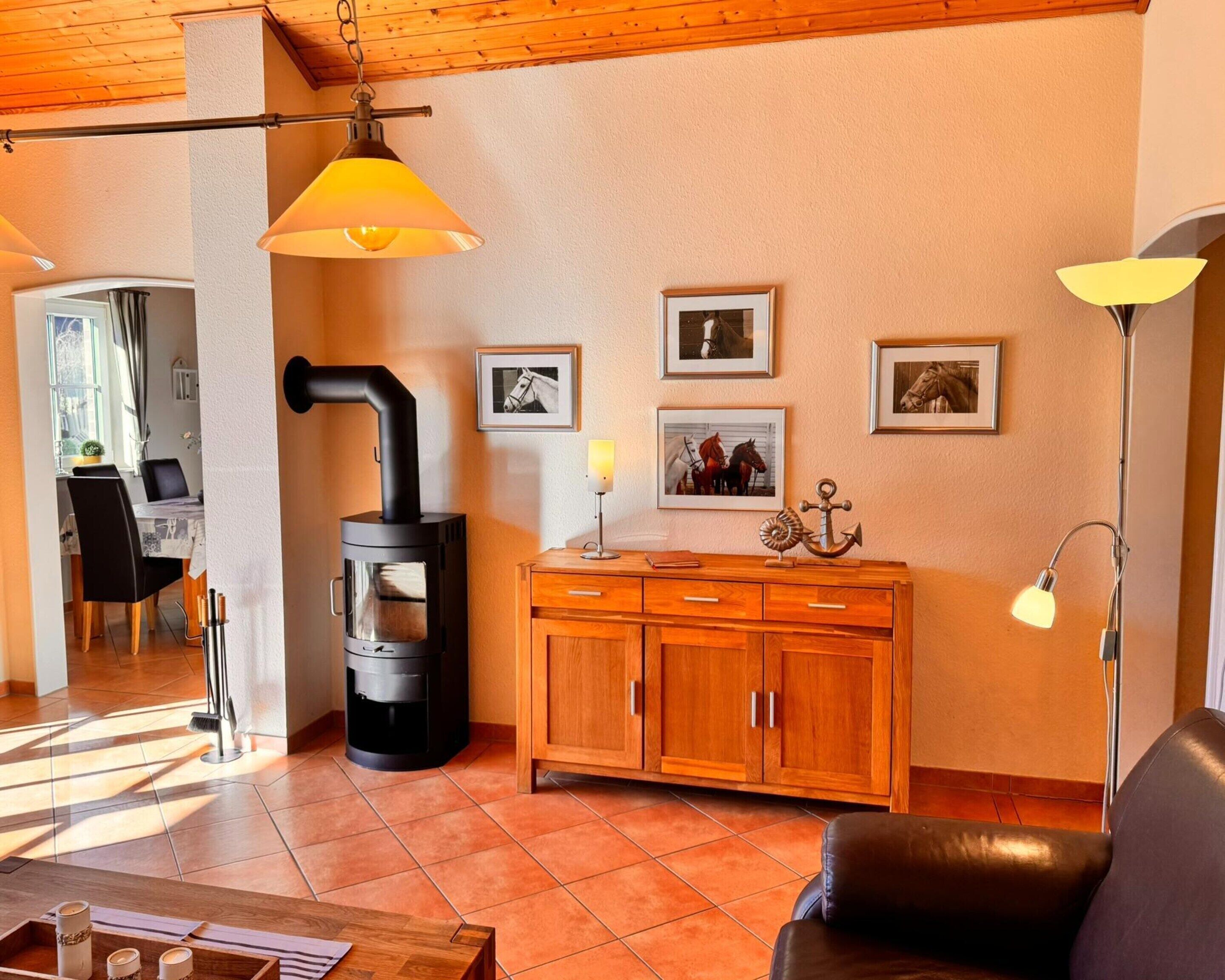 Un salon chaleureux avec un poêle à bois, des meubles en bois et un coin repas comprenant une table et des chaises.