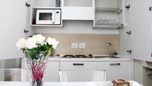 A compact kitchen with a microwave, sink, and storage cabinets.