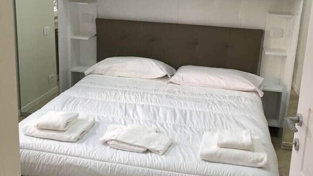 A bedroom with a bed, white headboard, and built-in shelving above the bed.